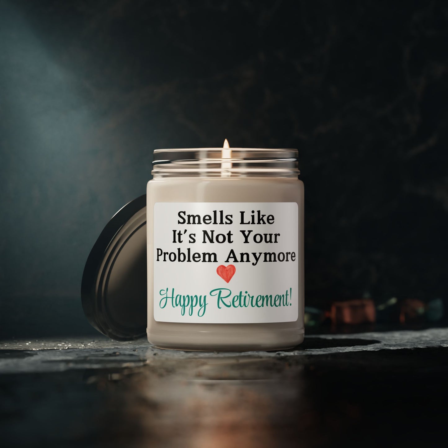 Glossy label retirement candle on a desk with festive decor.
