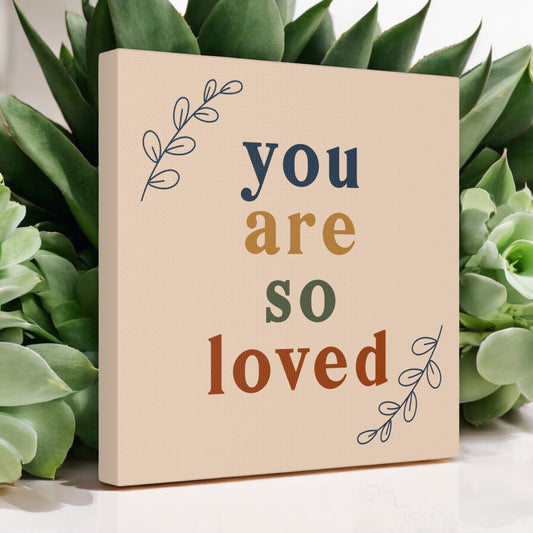 You are loved art with multicolor font on tan canvas
